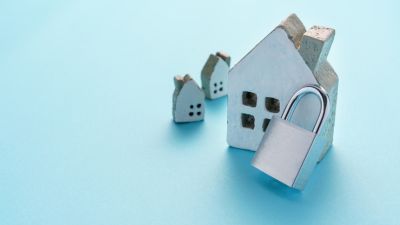 Casa em miniatura com cadeado representando segurança residencial - Casa em Dia Maia